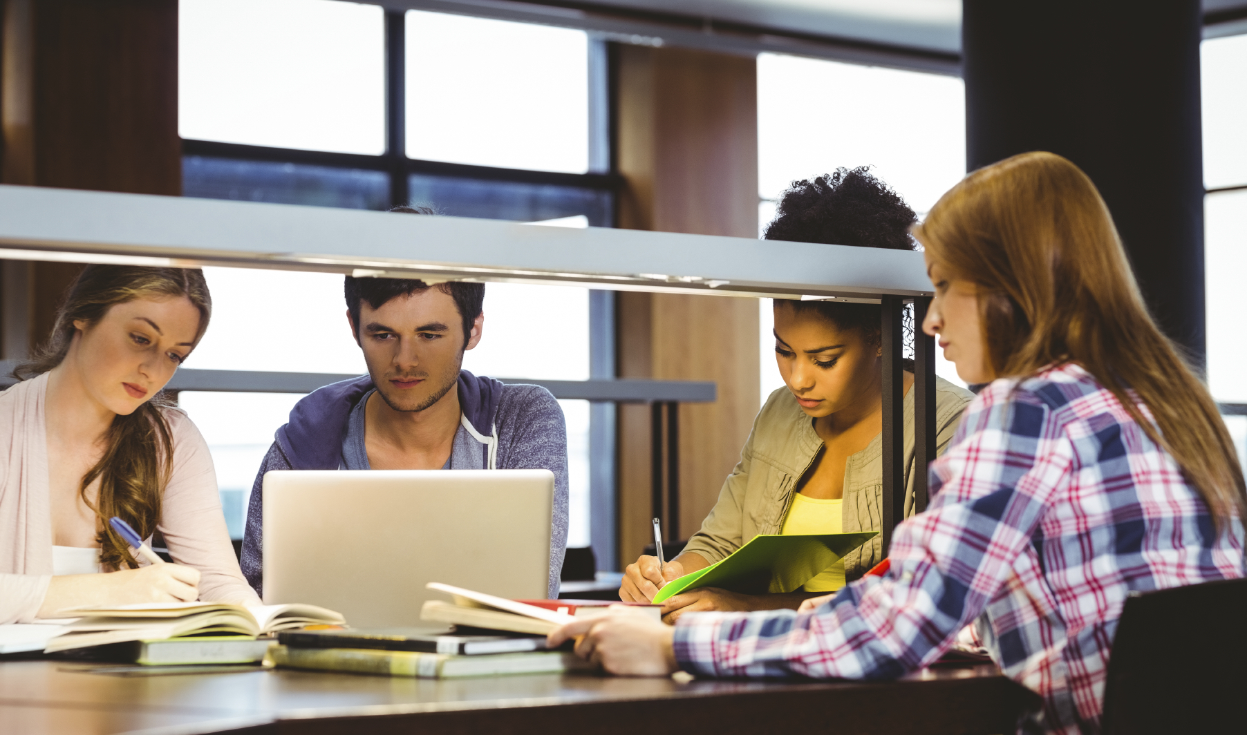 four students studying with laptop and books