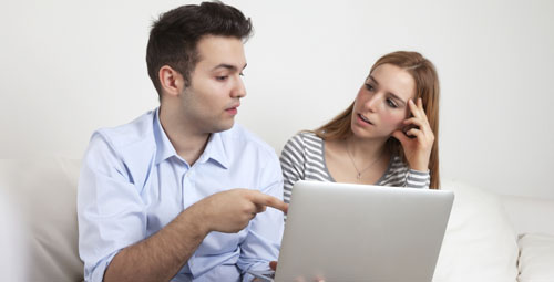 two people reading from a computer, as one person points to the screen