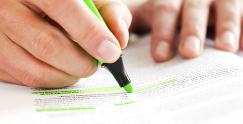 person using a highlighter marker to highlight words in a book