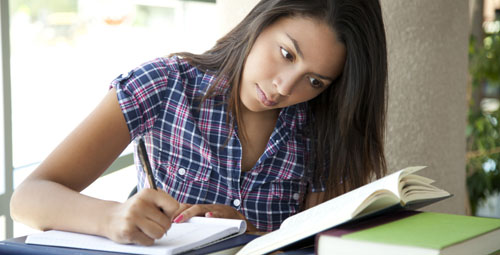 student reading from a book and writing information