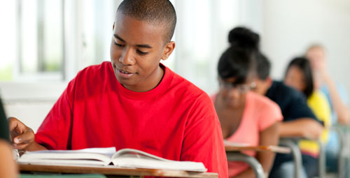 student reading from a book in a classroom