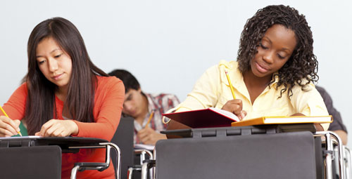 two students in a classroom reading and writing
